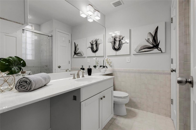 bathroom featuring toilet, vanity, visible vents, tile walls, and a shower stall