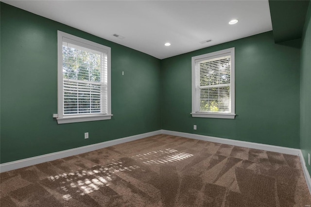 carpeted empty room with plenty of natural light, visible vents, and baseboards