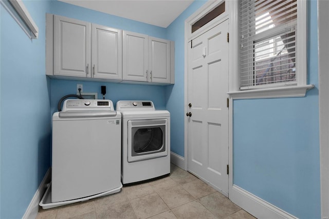 laundry room with baseboards, light tile patterned floors, cabinet space, and washer and dryer