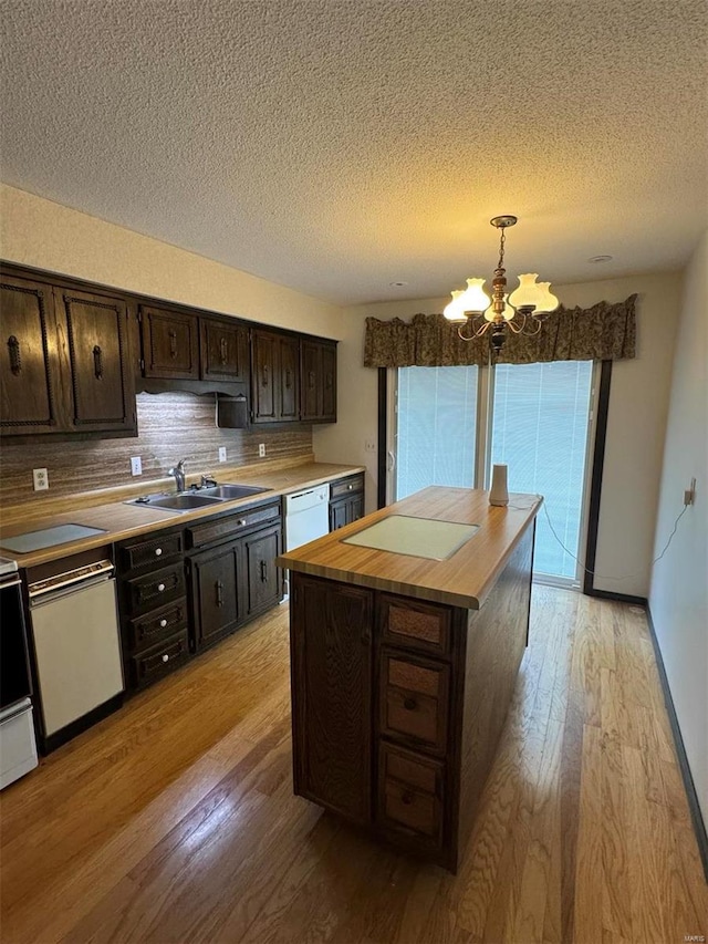 kitchen with white dishwasher, light wood-style flooring, butcher block countertops, and a sink