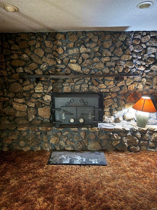 interior details featuring a wood stove, carpet flooring, and a textured ceiling