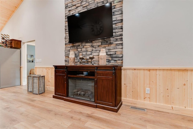 interior space with light hardwood / wood-style flooring, wood walls, and a fireplace