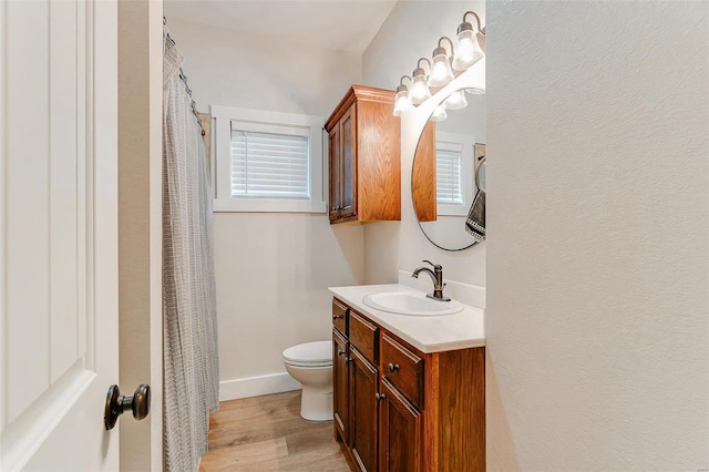 bathroom with hardwood / wood-style floors, toilet, plenty of natural light, and vanity