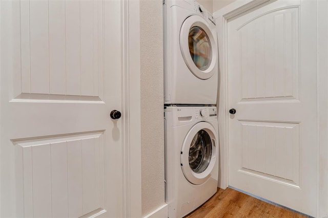 laundry room featuring stacked washing maching and dryer and light wood-type flooring