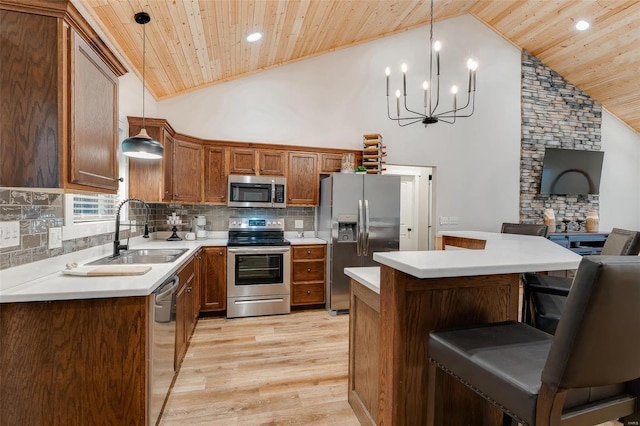 kitchen with hanging light fixtures, an inviting chandelier, light hardwood / wood-style flooring, stainless steel appliances, and high vaulted ceiling