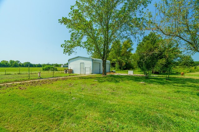 view of yard with a garage, a rural view, and an outdoor structure