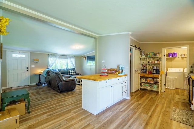 kitchen featuring light hardwood / wood-style flooring, ornamental molding, separate washer and dryer, a barn door, and wooden counters