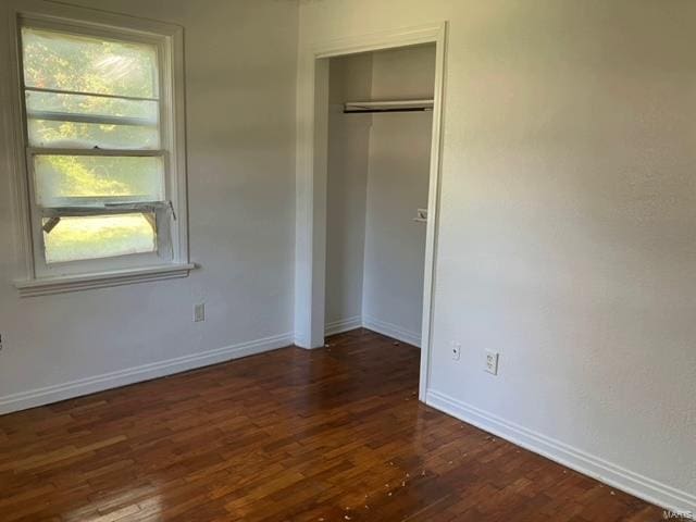 unfurnished bedroom featuring a closet and dark hardwood / wood-style floors