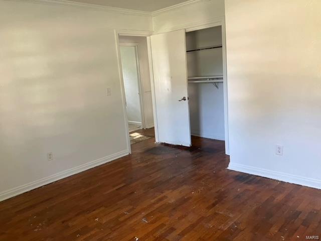 unfurnished bedroom with hardwood / wood-style floors, crown molding, and a closet