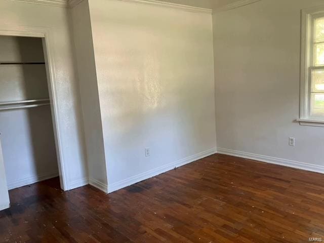 unfurnished bedroom with a closet, ornamental molding, and dark hardwood / wood-style flooring