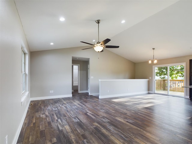 unfurnished room featuring ceiling fan with notable chandelier, dark hardwood / wood-style floors, and vaulted ceiling