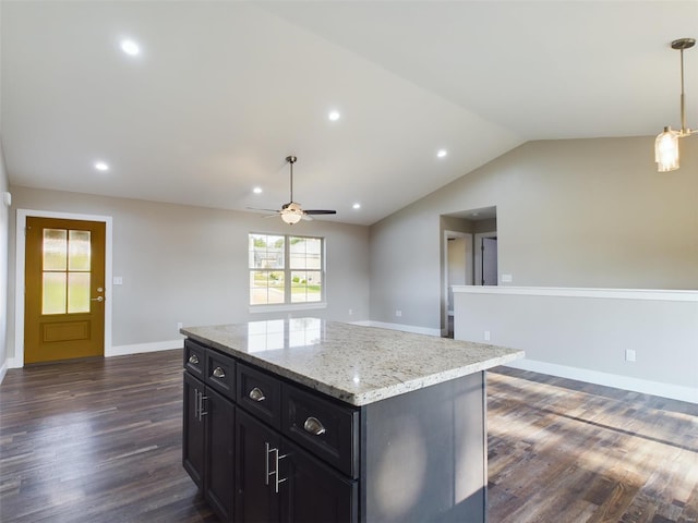 kitchen featuring ceiling fan, a kitchen island, dark hardwood / wood-style flooring, hanging light fixtures, and light stone counters