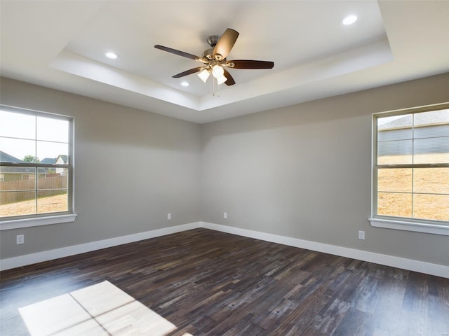 empty room with ceiling fan, a raised ceiling, and hardwood / wood-style floors