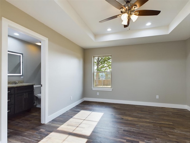 spare room featuring ceiling fan, dark hardwood / wood-style flooring, sink, and a tray ceiling