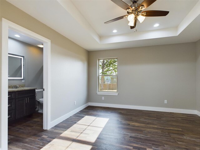 spare room with ceiling fan, dark wood-type flooring, and a raised ceiling