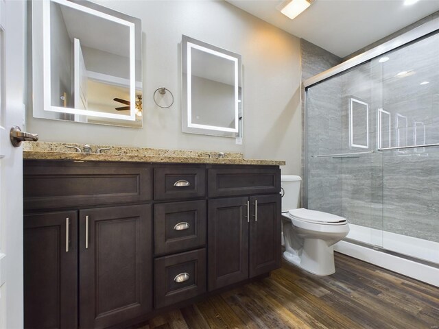 bathroom with toilet, wood-type flooring, vanity, and a shower with door