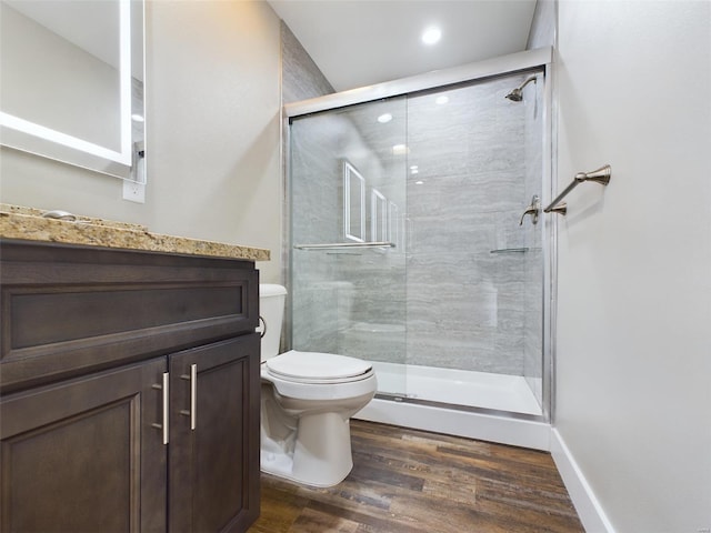 bathroom featuring hardwood / wood-style flooring, toilet, a shower with door, and vanity