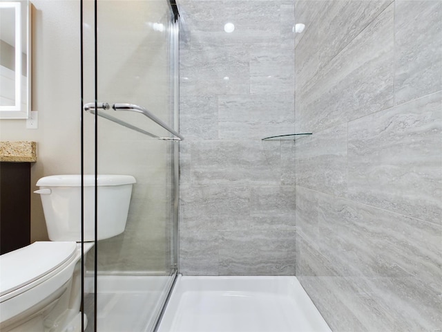 bathroom featuring a shower with shower door, vanity, and toilet