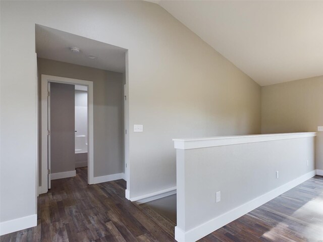 corridor with lofted ceiling and dark hardwood / wood-style floors