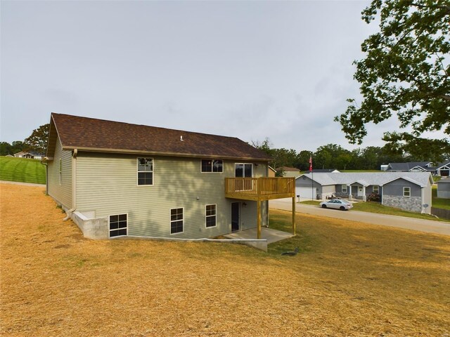 rear view of property with a wooden deck and a lawn