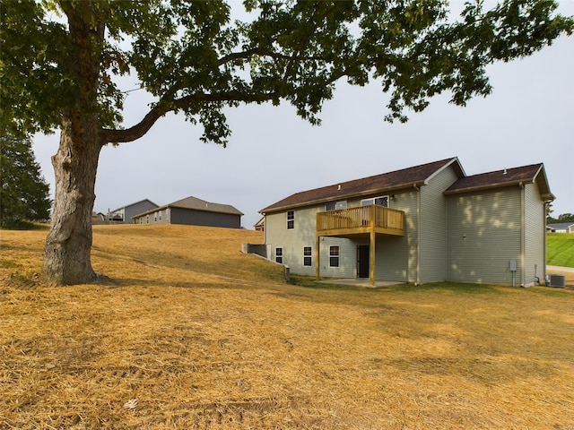 rear view of house featuring a yard, central AC, and a balcony