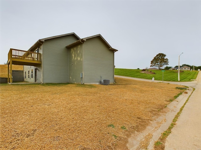 view of home's exterior with a lawn, central AC unit, and a deck