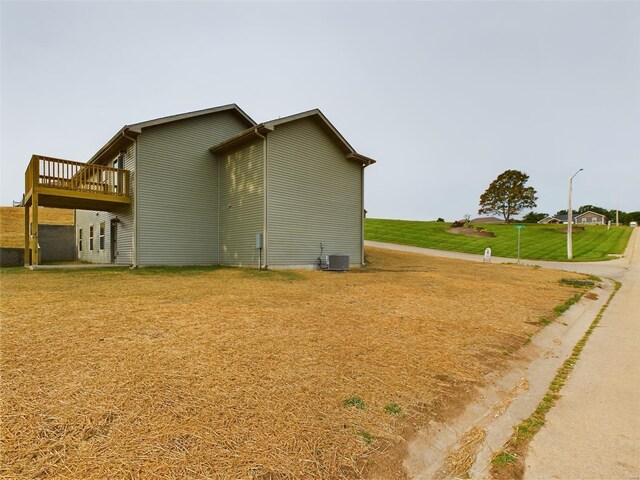 view of home's exterior with central AC unit, a lawn, and a wooden deck