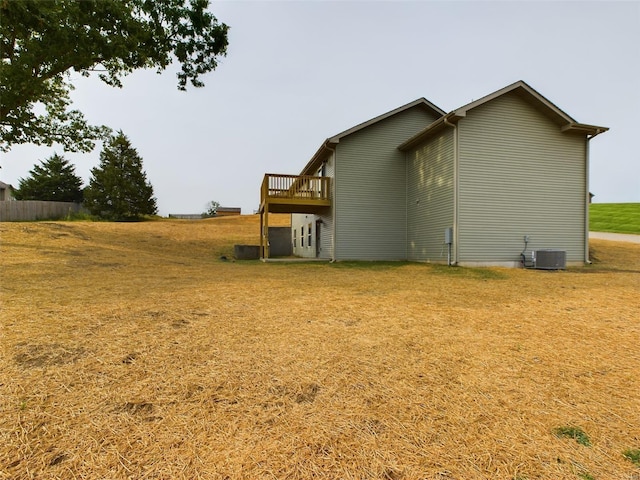 view of property exterior with a deck, a lawn, and cooling unit