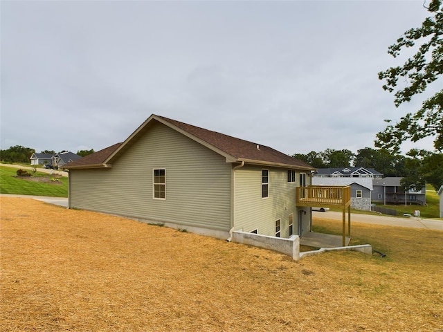 view of property exterior featuring a wooden deck and a lawn