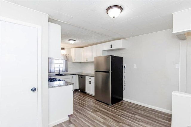 kitchen featuring sink, light wood-type flooring, tasteful backsplash, white cabinetry, and stainless steel appliances