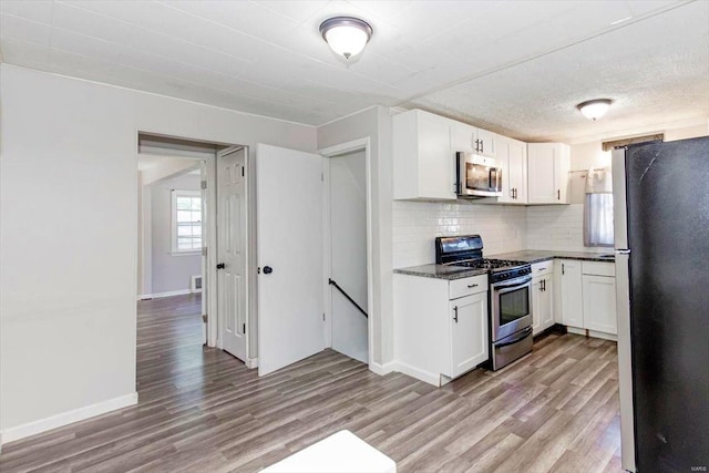 kitchen featuring appliances with stainless steel finishes, light hardwood / wood-style flooring, white cabinetry, and tasteful backsplash