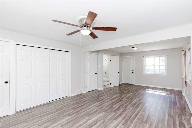 unfurnished bedroom with ceiling fan, multiple closets, and light hardwood / wood-style flooring