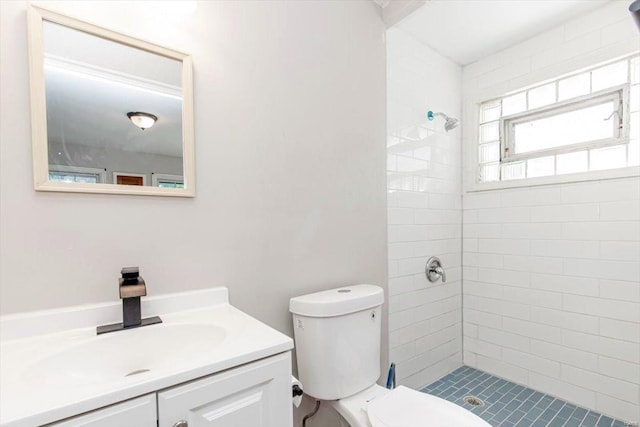 bathroom featuring toilet, tiled shower, and vanity