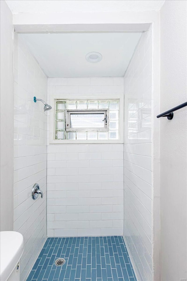 bathroom with toilet and a tile shower