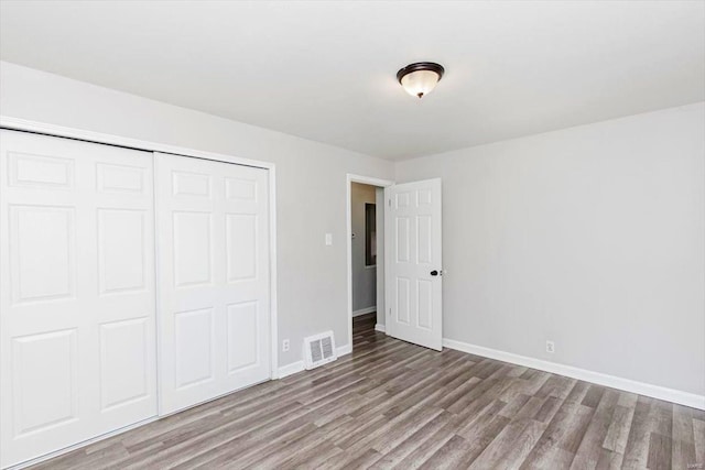 unfurnished bedroom with hardwood / wood-style flooring and a closet