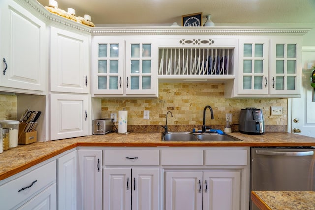 kitchen featuring sink, white cabinetry, stainless steel dishwasher, and backsplash