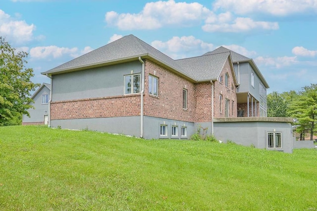 view of side of property featuring a shingled roof, a yard, and brick siding