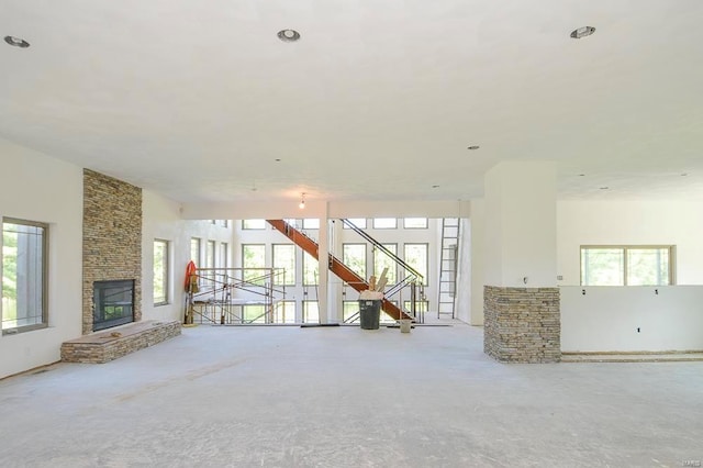 unfurnished living room with plenty of natural light, stairs, and a large fireplace