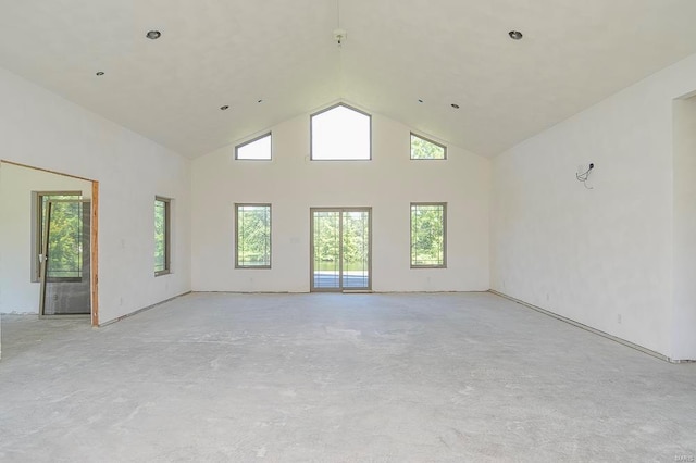 empty room featuring high vaulted ceiling, plenty of natural light, and unfinished concrete floors