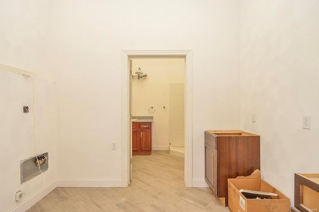 clothes washing area with baseboards and light wood-type flooring