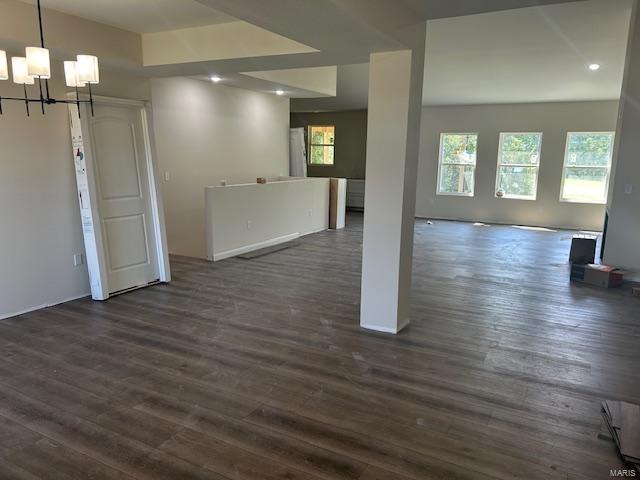 spare room with a notable chandelier and dark hardwood / wood-style floors