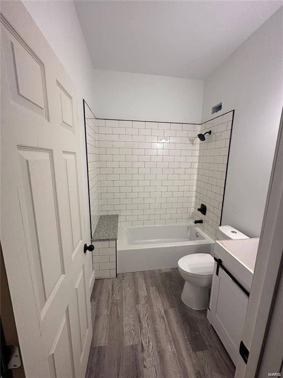 full bathroom with toilet, tiled shower / bath combo, hardwood / wood-style flooring, and vanity