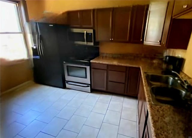 kitchen with sink, light tile patterned flooring, range, and stone countertops