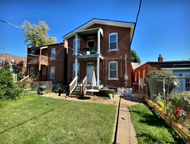 back of house with a balcony and a yard