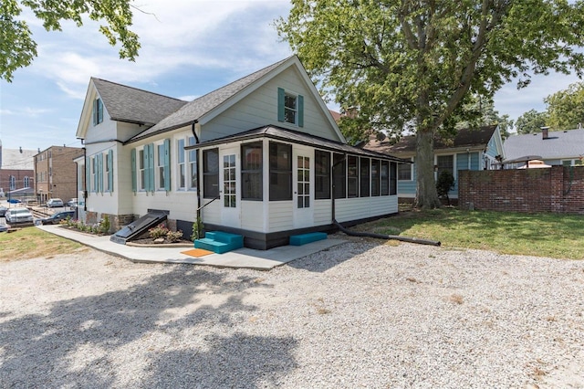 view of front of house with a sunroom, a shingled roof, fence, and a front yard