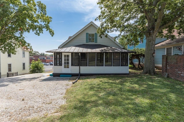 rear view of property featuring a sunroom, metal roof, a lawn, and a standing seam roof