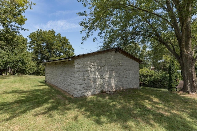 view of side of property featuring an outbuilding, a yard, and fence