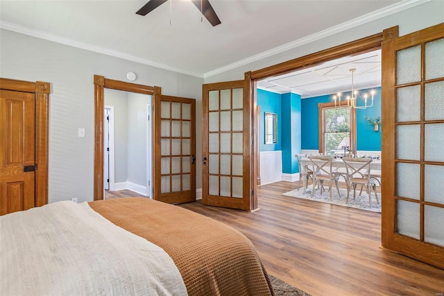 bedroom featuring french doors, ornamental molding, wood finished floors, a chandelier, and baseboards