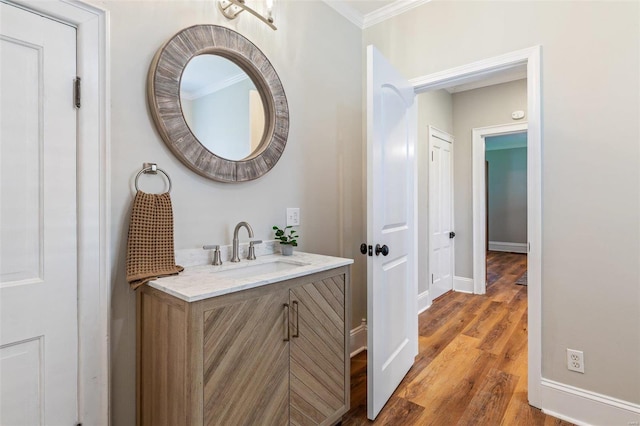 bathroom with crown molding, baseboards, wood finished floors, and vanity