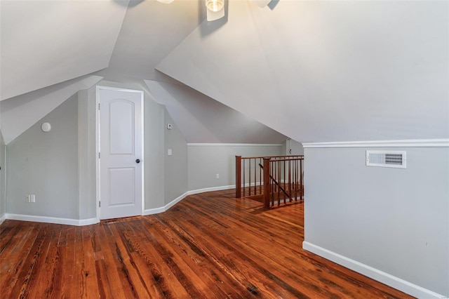 additional living space with baseboards, visible vents, vaulted ceiling, and wood finished floors